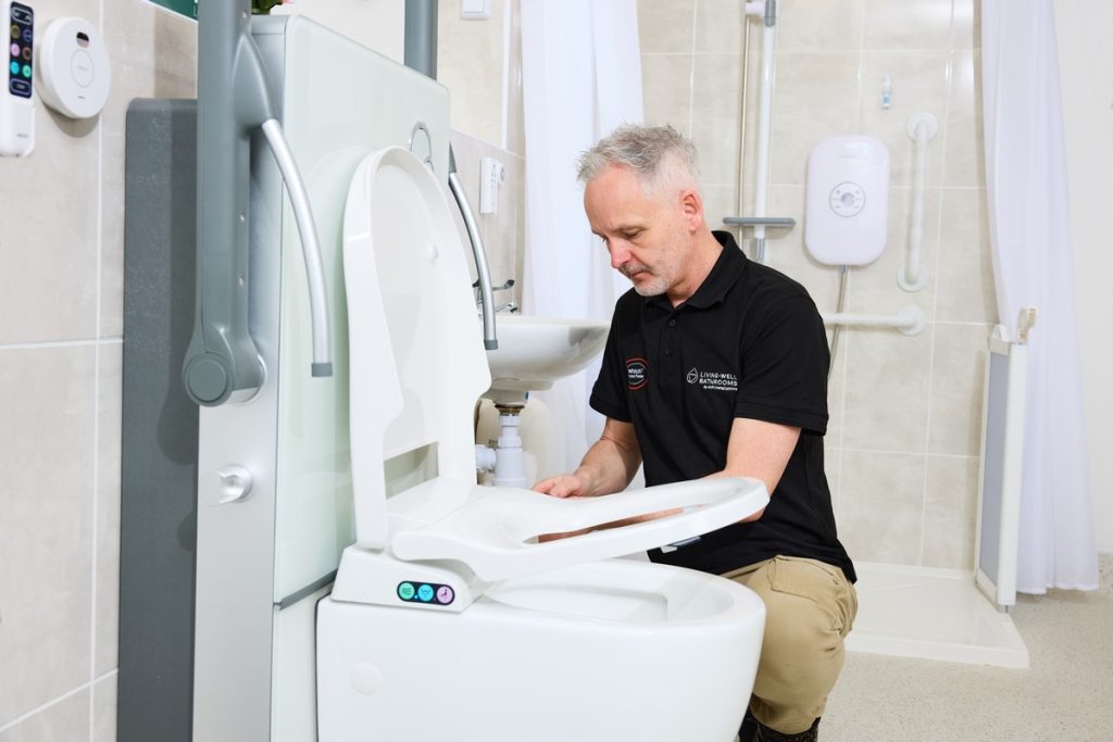 Living Well Bathrooms installer fitting a new toilet into a bathroom